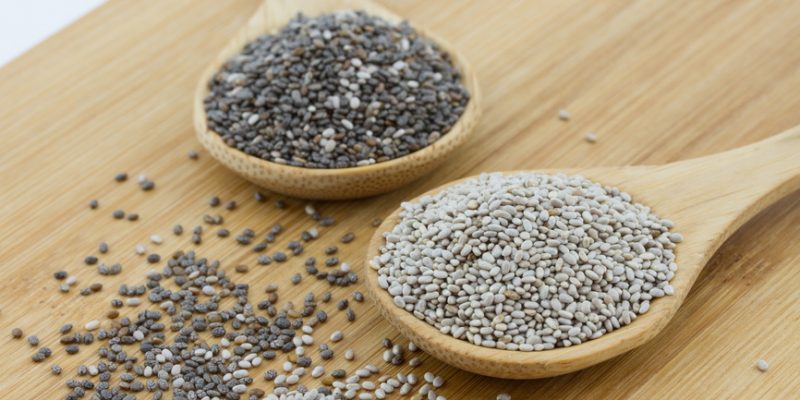 black and white chia seeds on wooden underground
